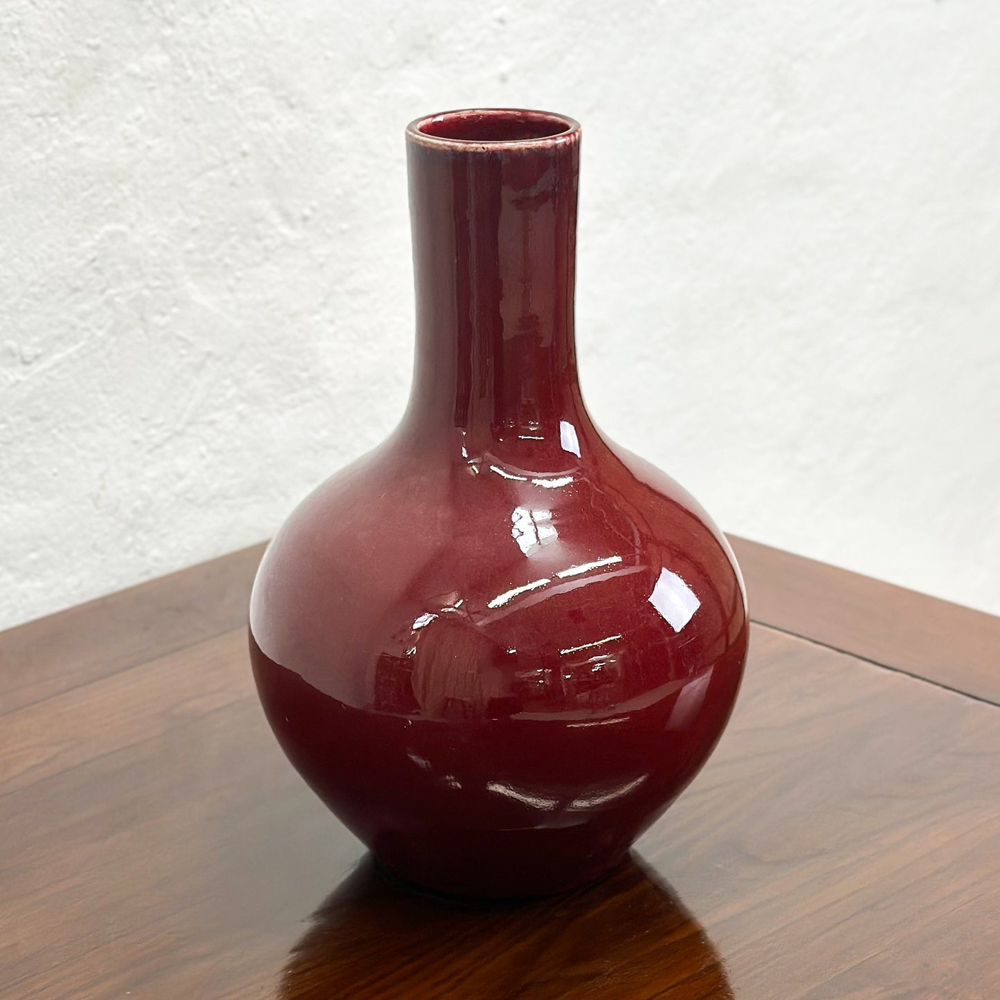 A burgundy.globular vase displayed against a neutral background.