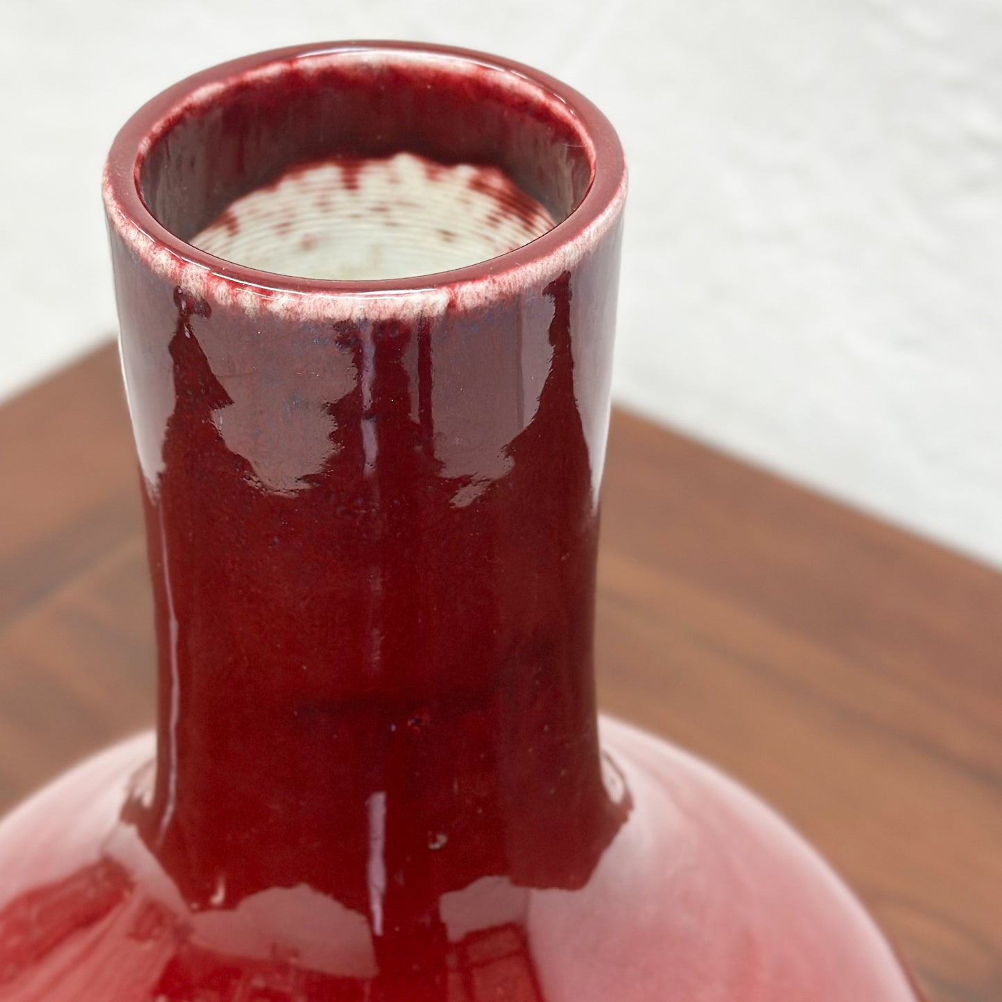 A burgundy.globular vase displayed against a neutral background.