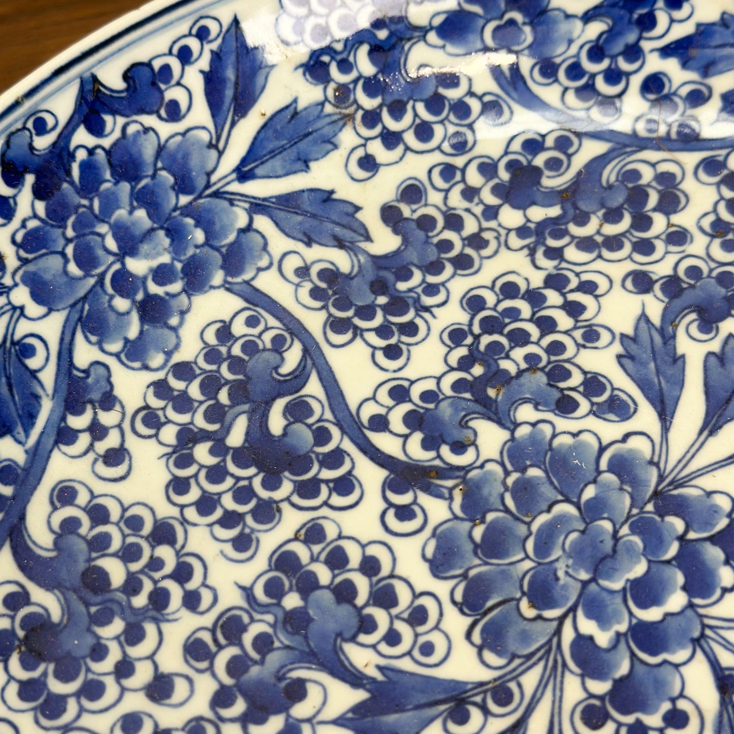 A round porcelain plate with blue floral patterns on a white background, displayed on a wooden surface.