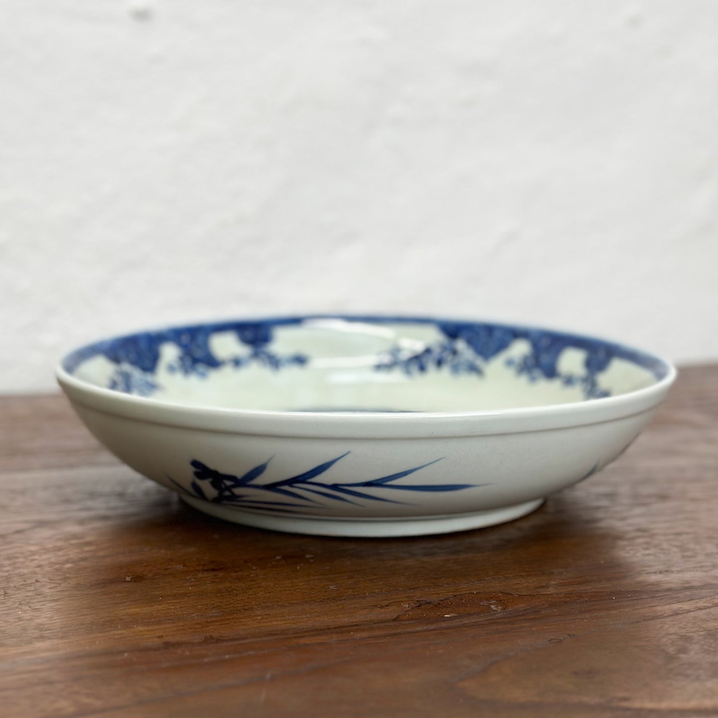 A round porcelain plate with blue floral patterns on a white background, displayed on a wooden surface.