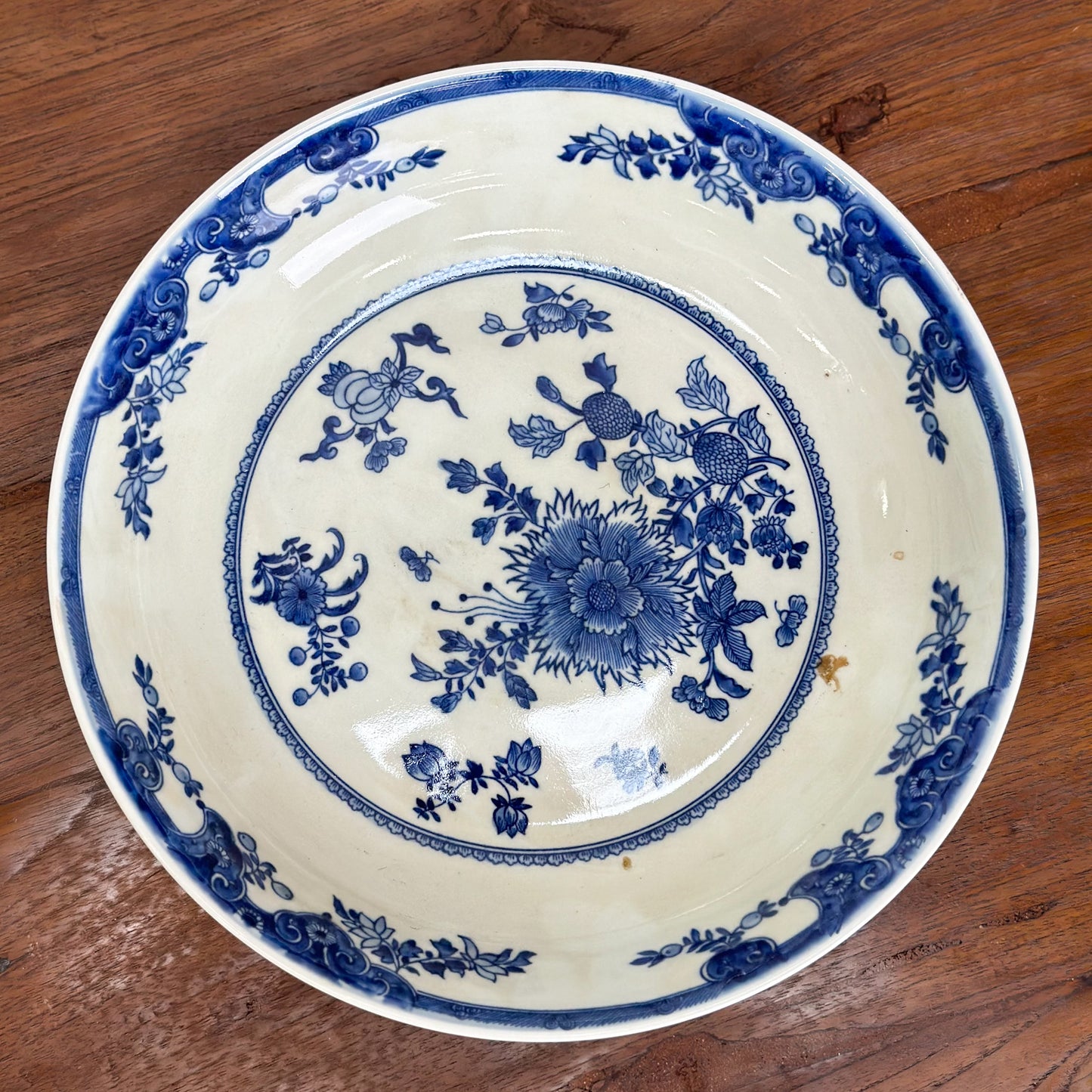 A round porcelain plate with blue floral patterns on a white background, displayed on a wooden surface.