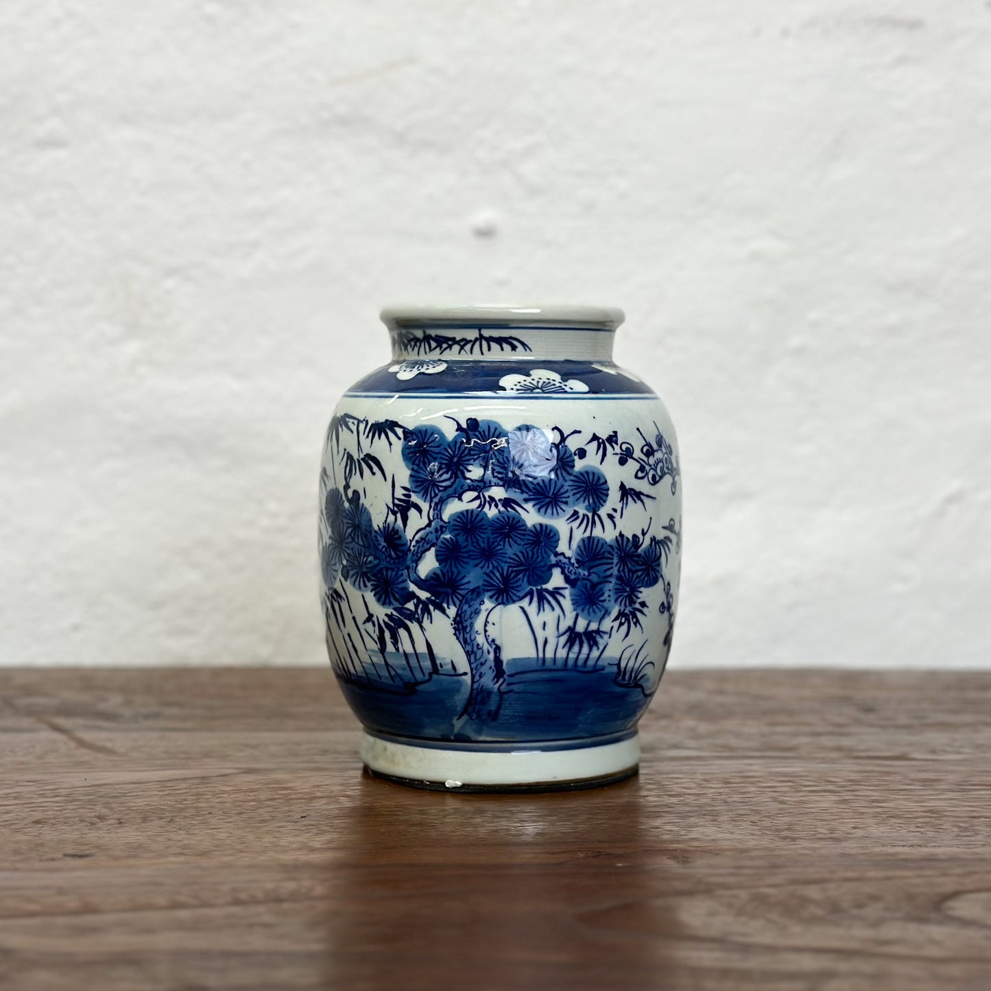 A blue and white porcelain vase with floral and tree patterns, displayed against a neutral background.