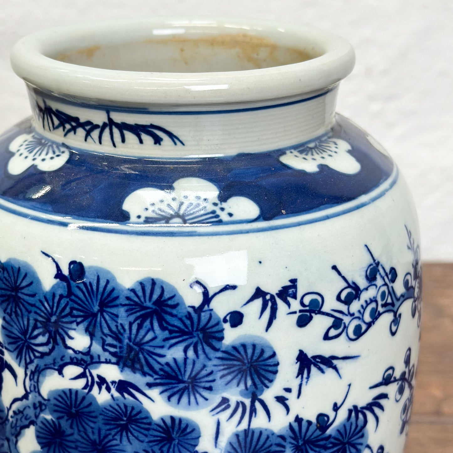 A blue and white porcelain vase with floral and tree patterns, displayed against a neutral background.