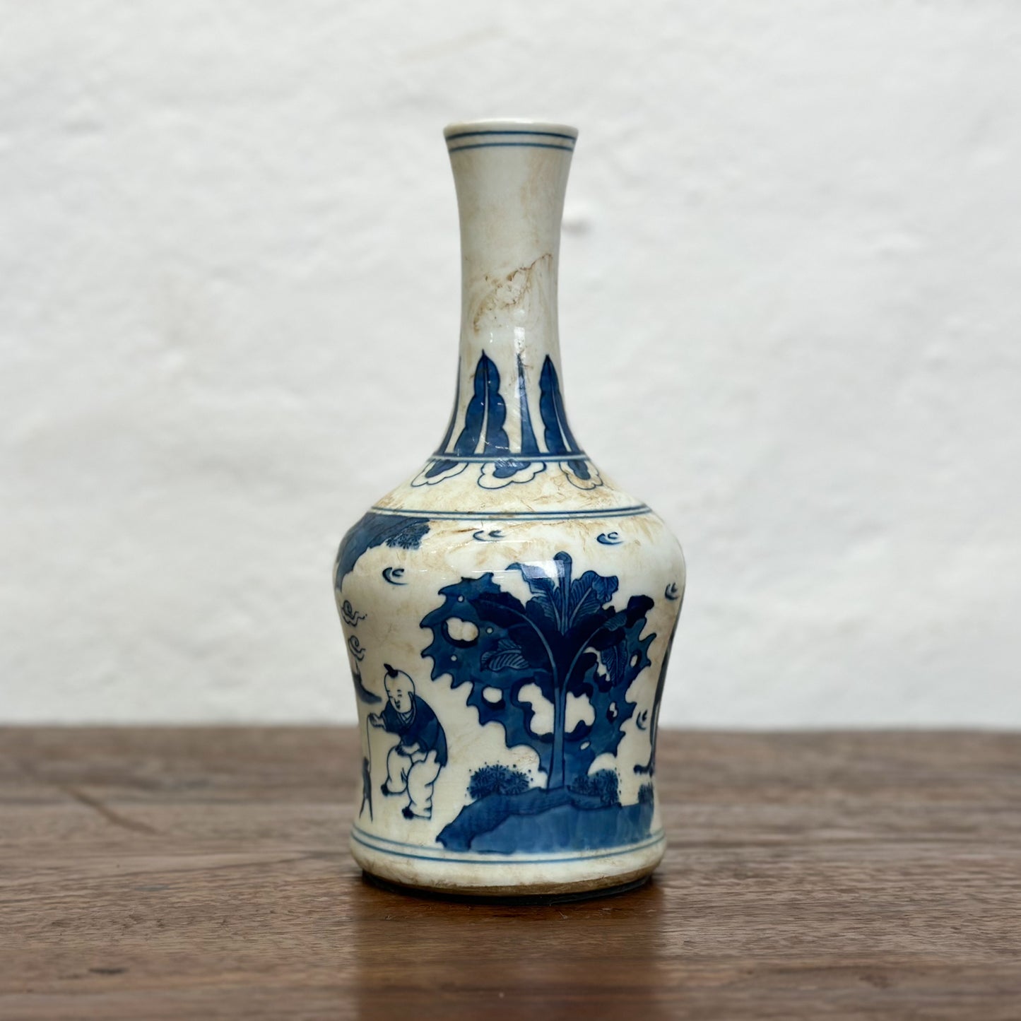 A blue and white porcelain vase with figural long neck design, depicting characters in a traditional setting.