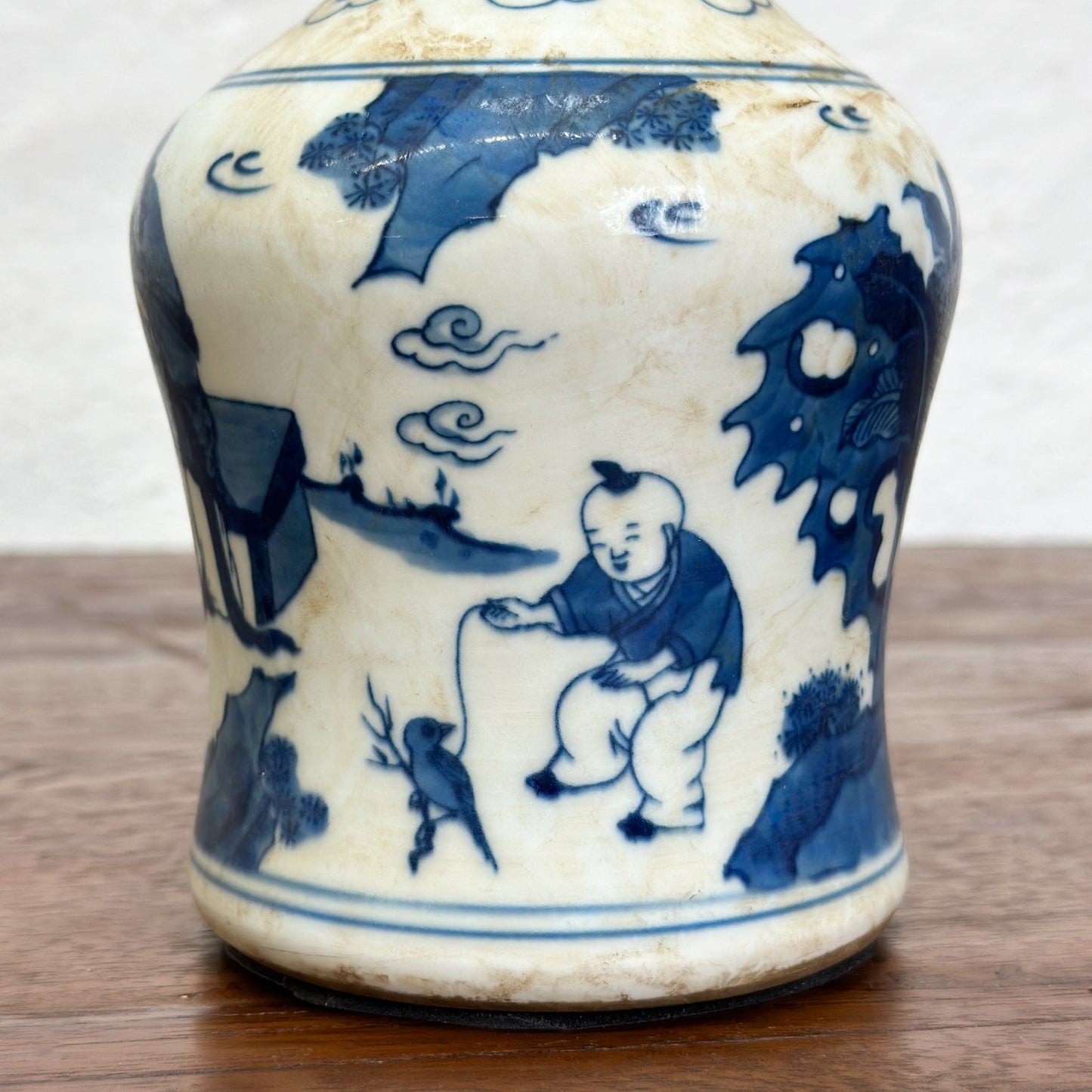 A blue and white porcelain vase with figural long neck design, depicting characters in a traditional setting.