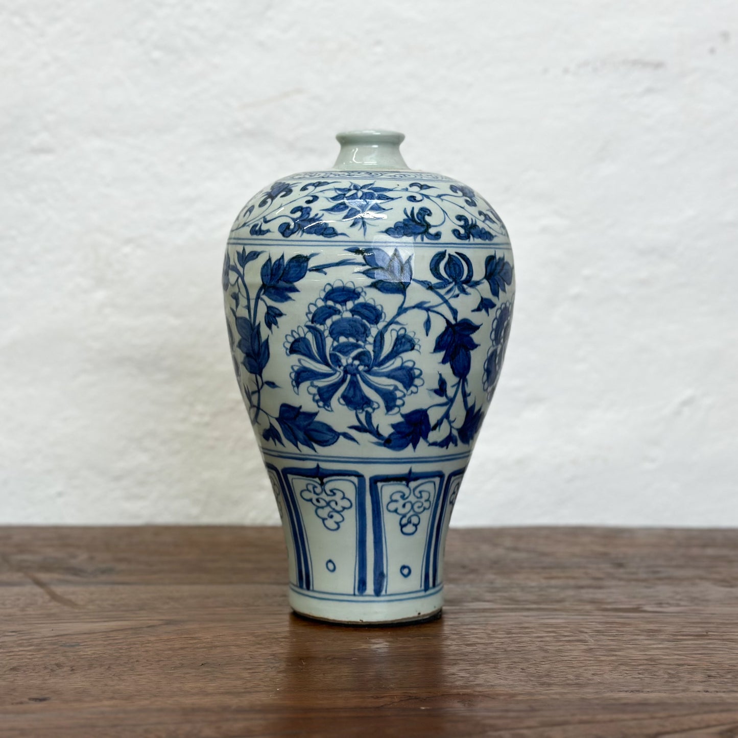 A blue and white ceramic vase with floral patterns, displayed against a neutral background.
