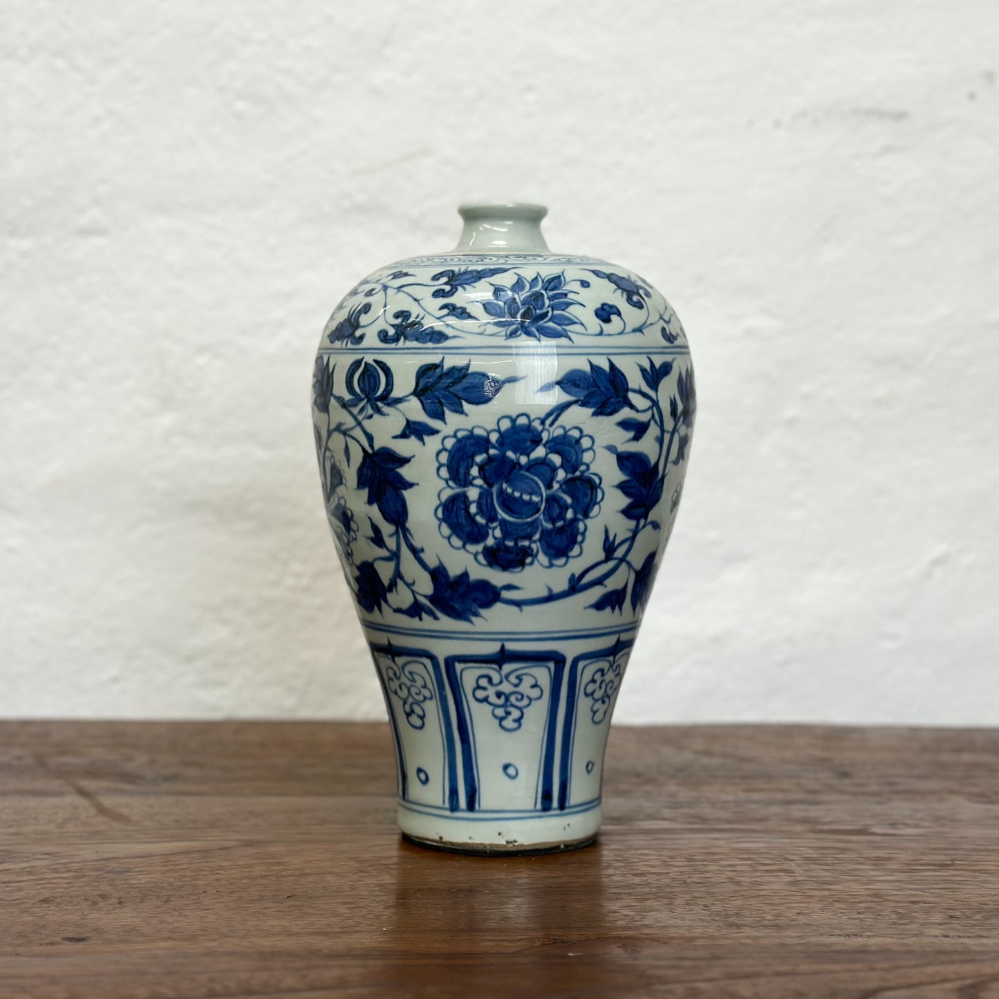 A blue and white ceramic vase with floral patterns, displayed against a neutral background.