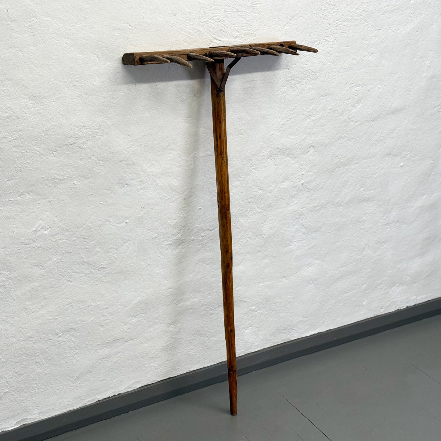 Wooden coat rack against a white wall