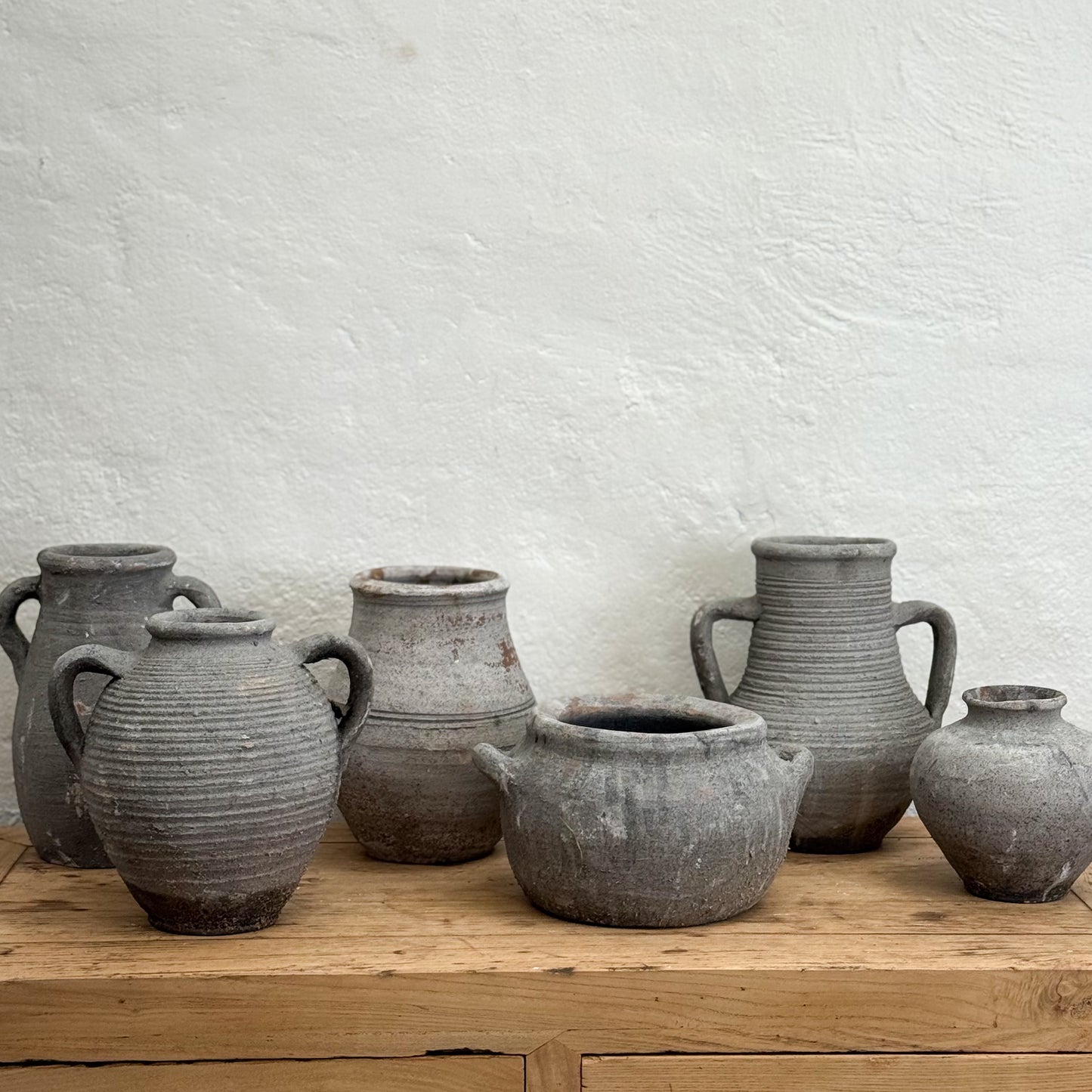 Set of gray ceramic pots on a wooden surface with a light gray background