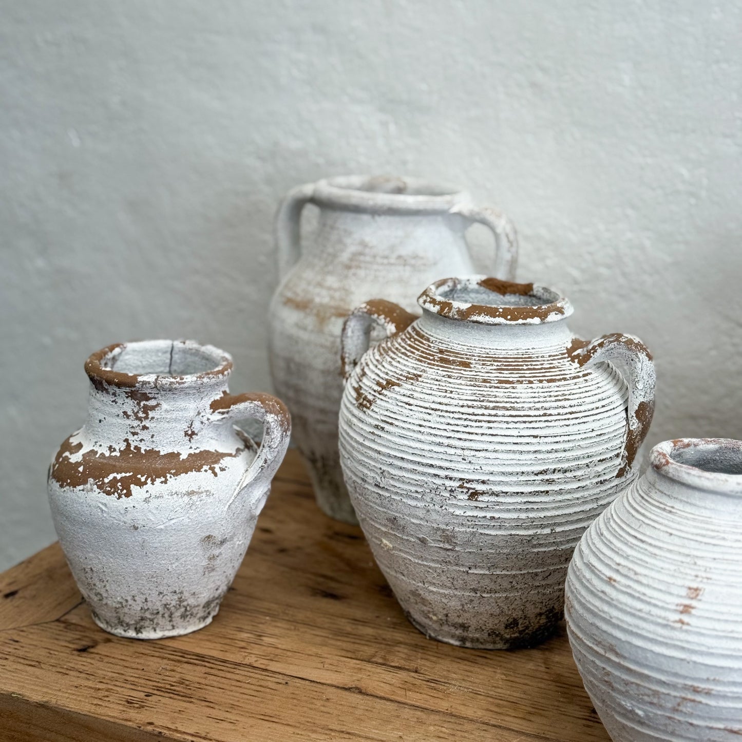 Set of rustic ceramic vases on a wooden surface with a neutral background