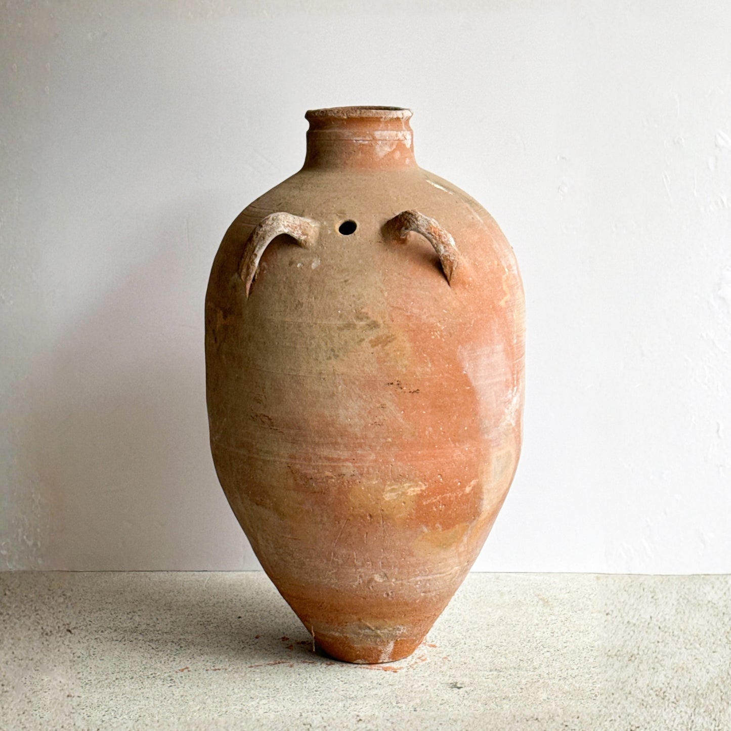 Terracotta vase with a textured surface on a light background