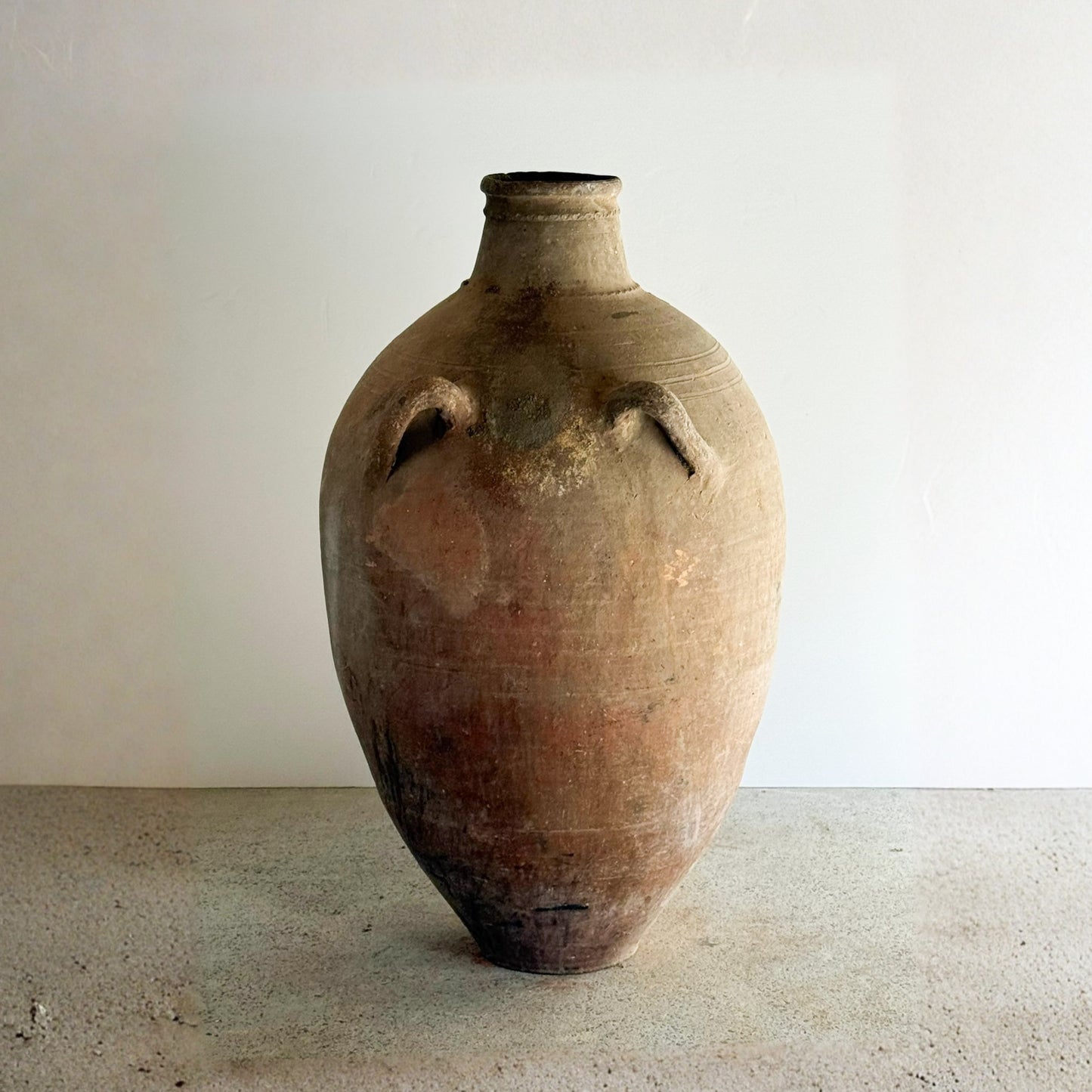 Vintage terracotta jar with handles on a plain background