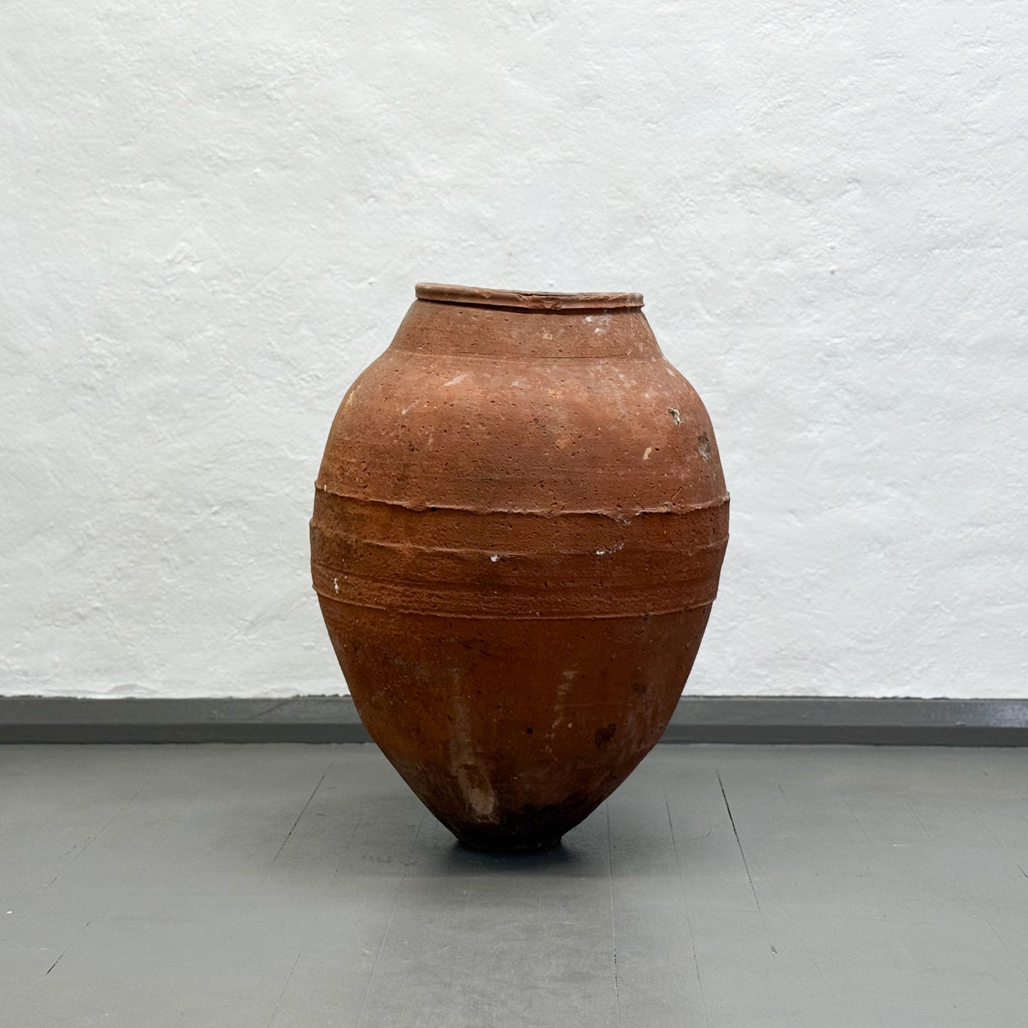 Large terracotta vase against a plain white wall