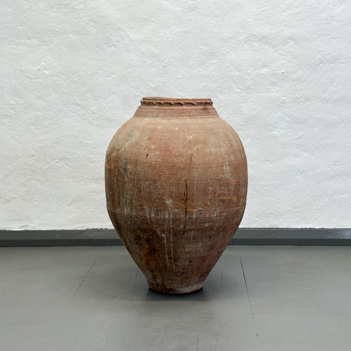 Large brown ceramic jar against a plain white wall