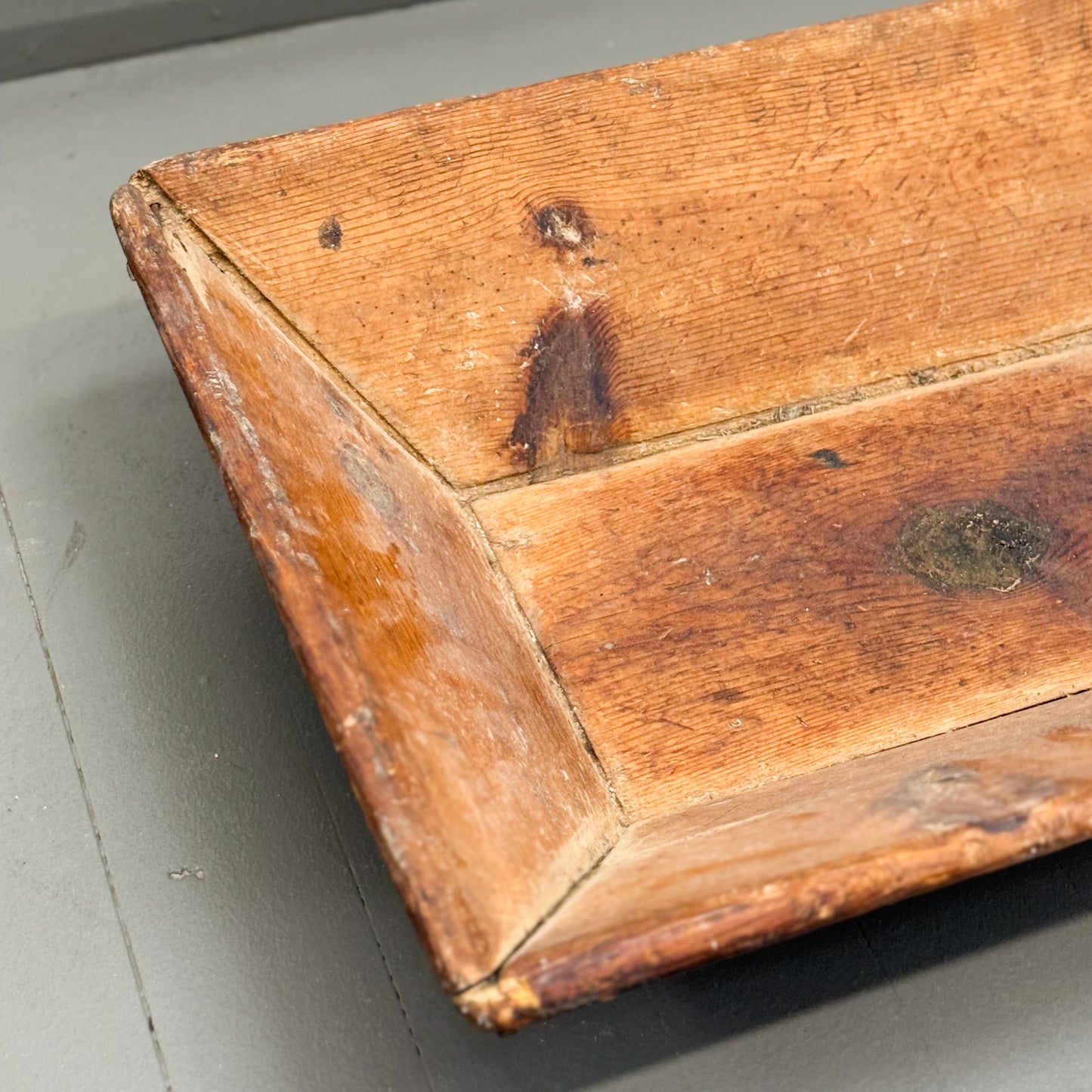 Close-up of a wooden box with visible wear on a gray surface