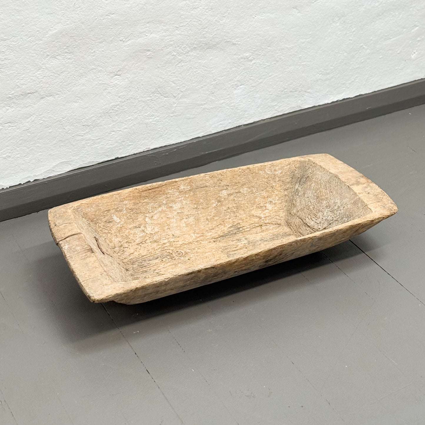 Wooden trough on a gray floor with a white wall background