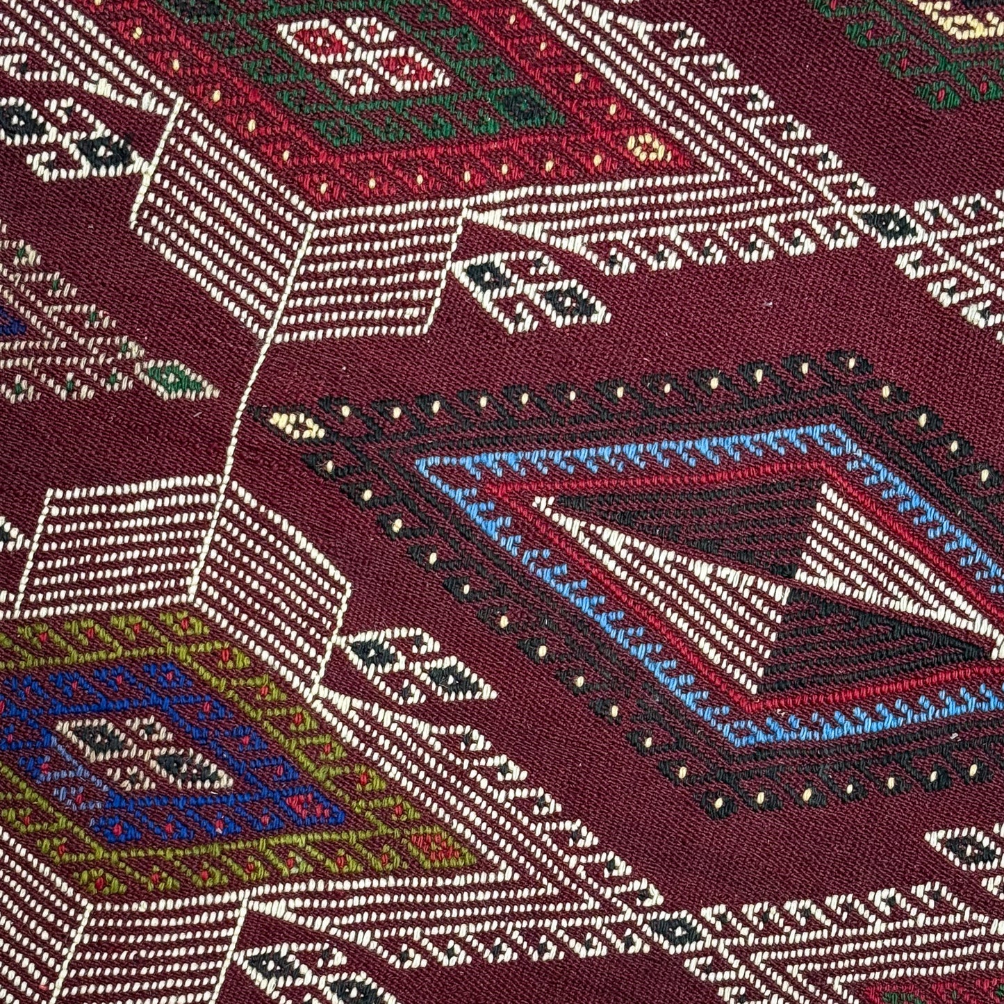 Close-up of a patterned fabric with geometric designs on a red background