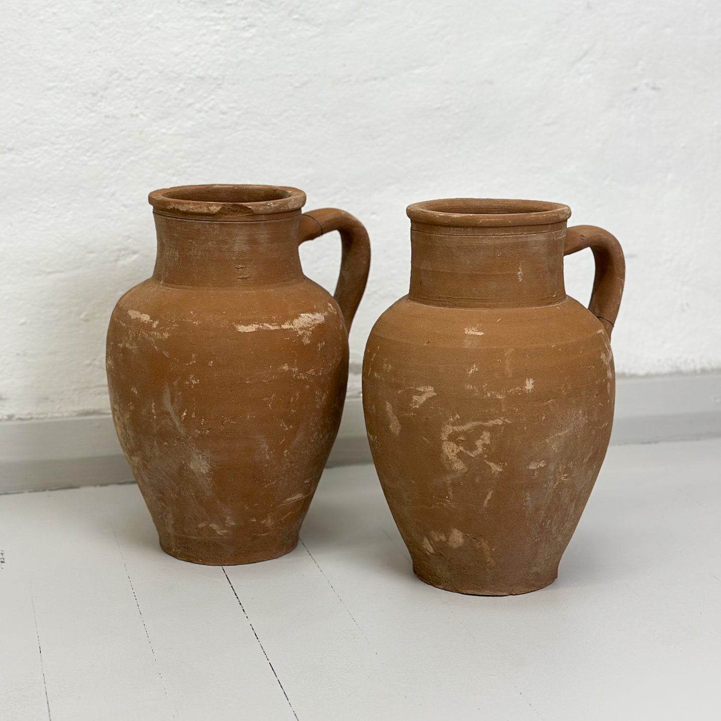 Two brown ceramic Turkish pots with a single handle on a white background.