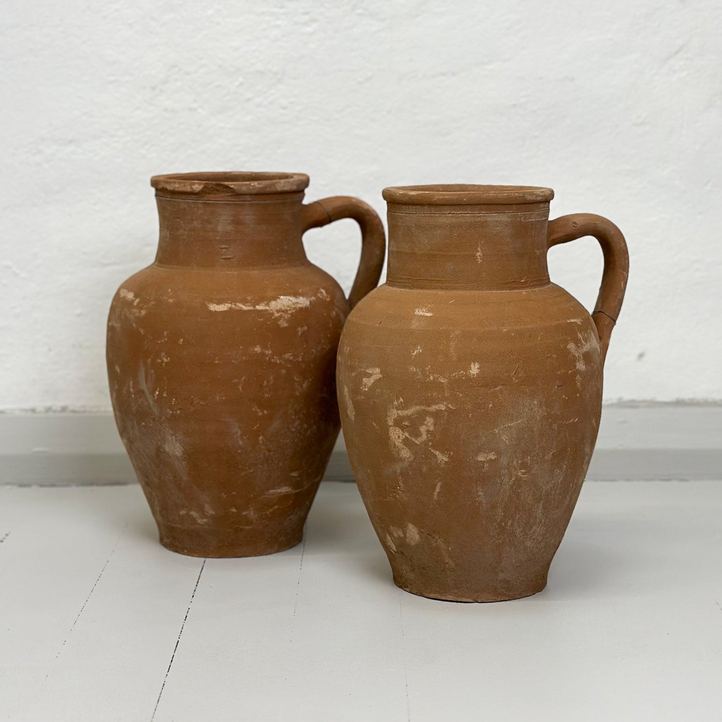 Two brown ceramic Turkish pots with a single handle on a white background.