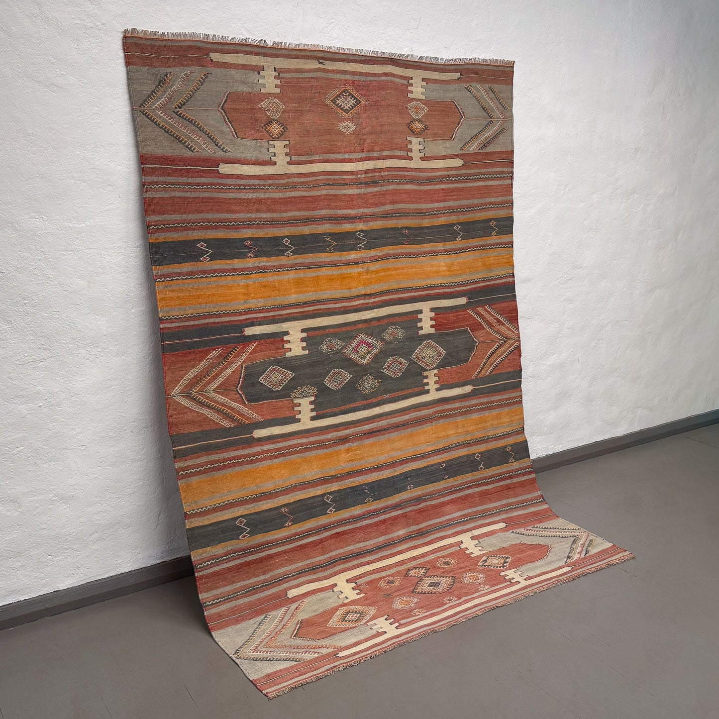 Patterned rug on a plain floor with a white wall background