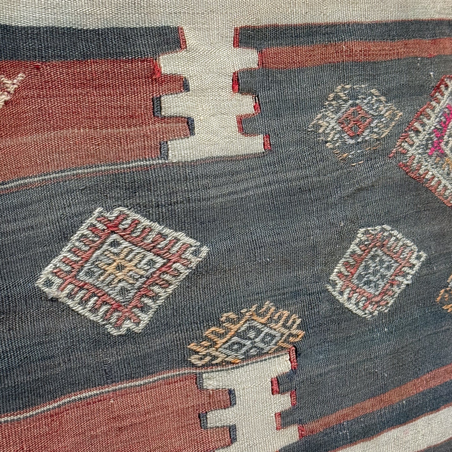 Close-up of a patterned fabric with geometric designs in red, blue, and white.