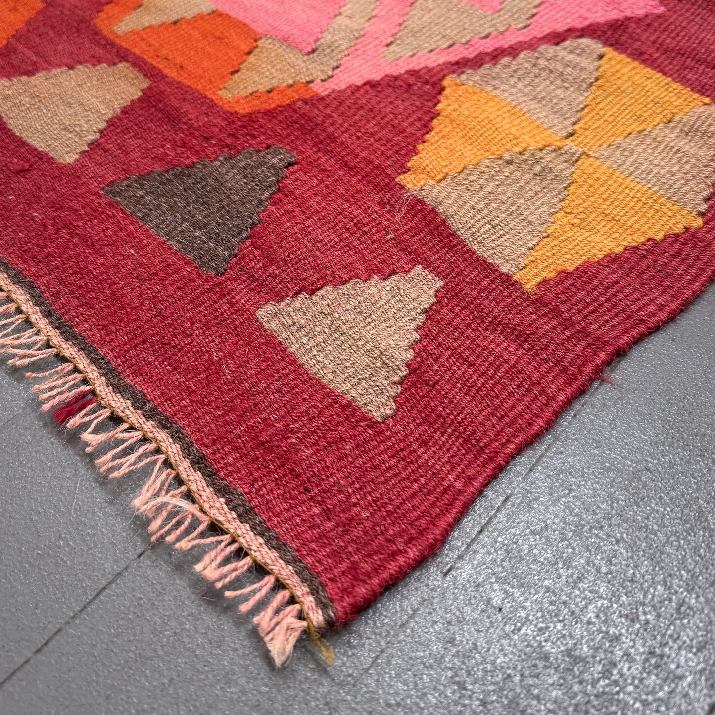 Close-up of a geometric patterned rug with triangles on a gray floor.