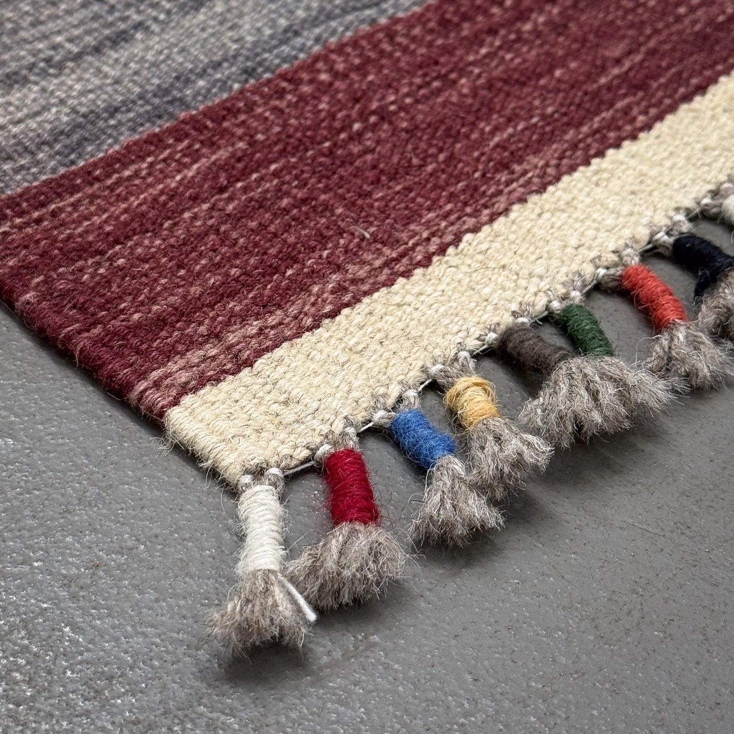 Textured rug with colorful tassels on a gray surface