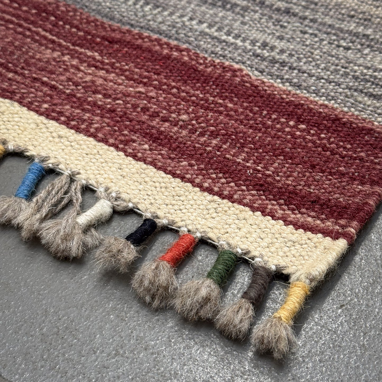 Striped rug with tassels on a gray surface