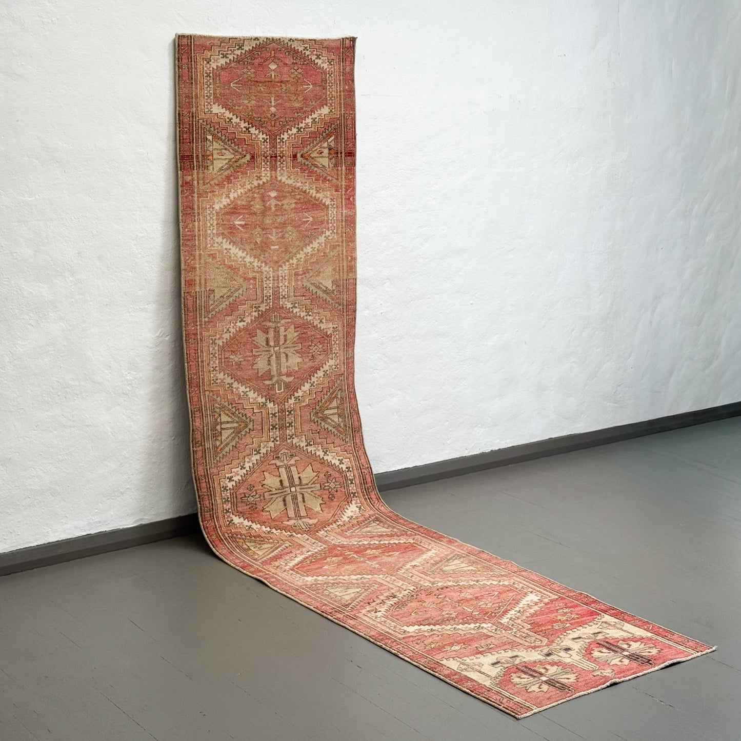 Long, patterned rug on a plain floor with a white wall background