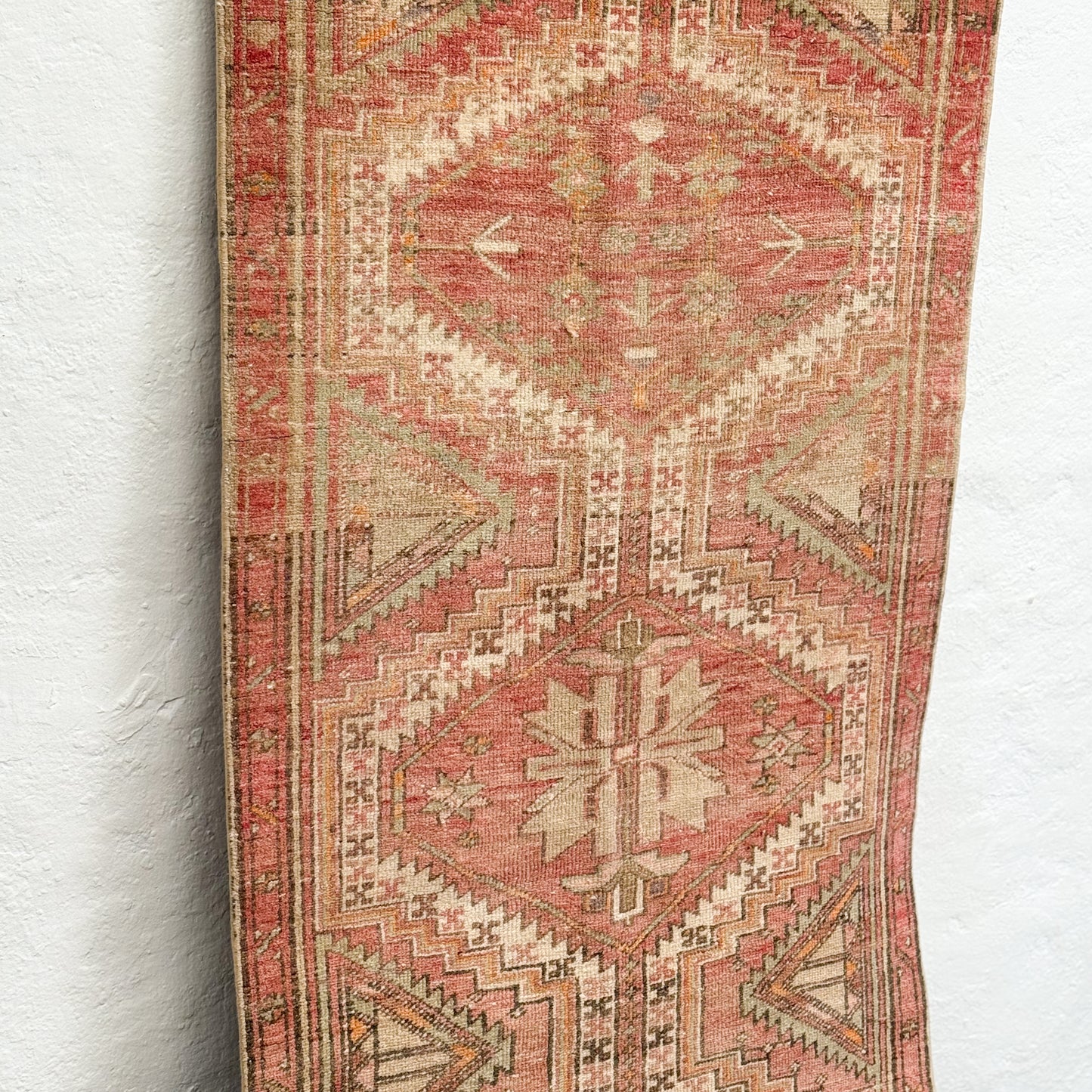 Vintage rug with intricate geometric pattern on a white wall