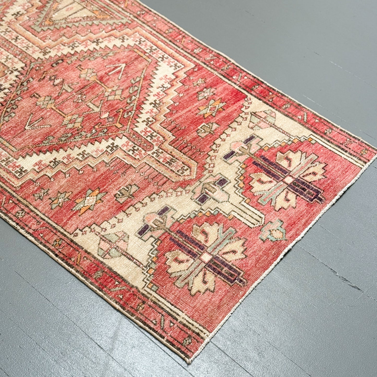 Vintage red and beige patterned rug on a gray floor