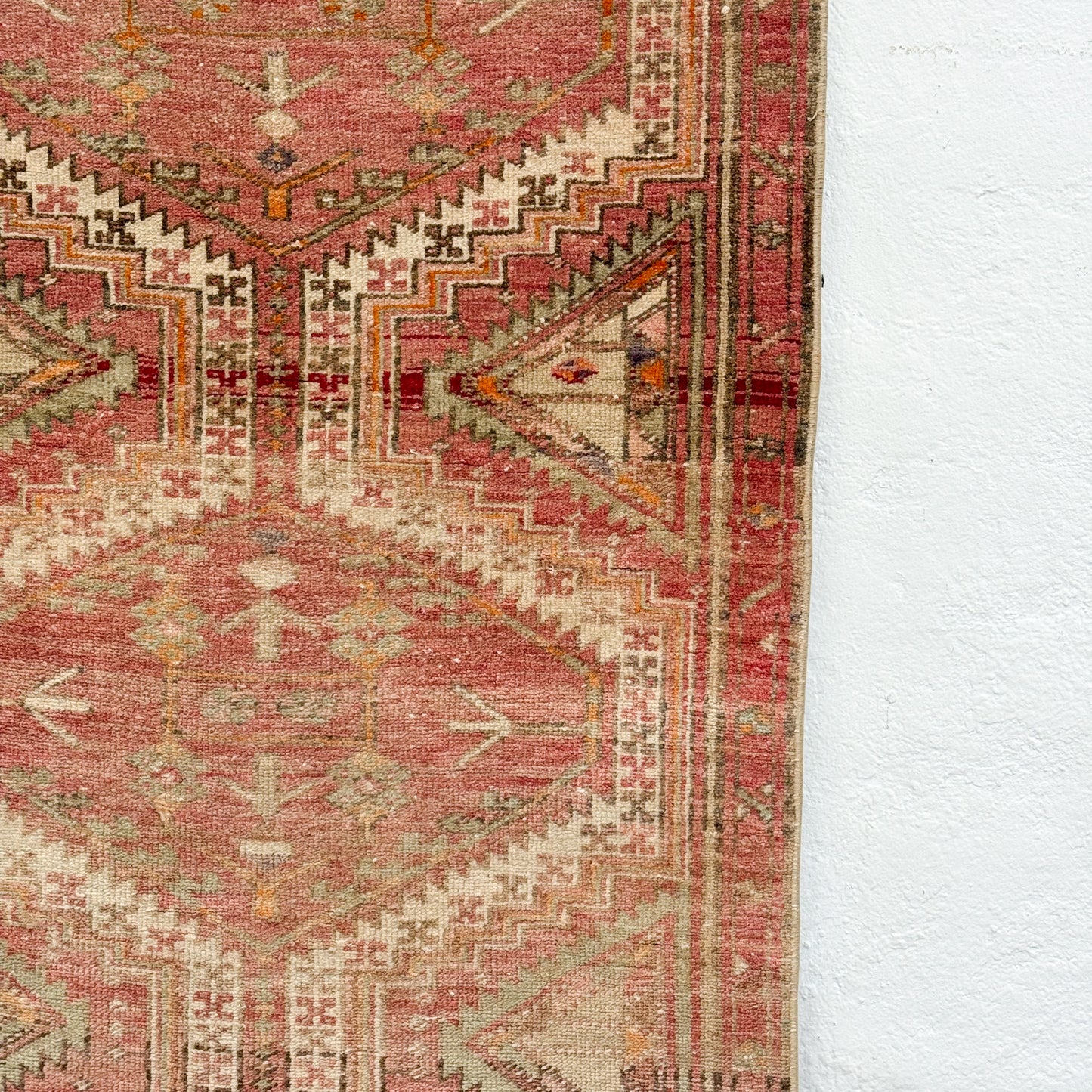 Close-up of a patterned rug with red and beige colors on a white background