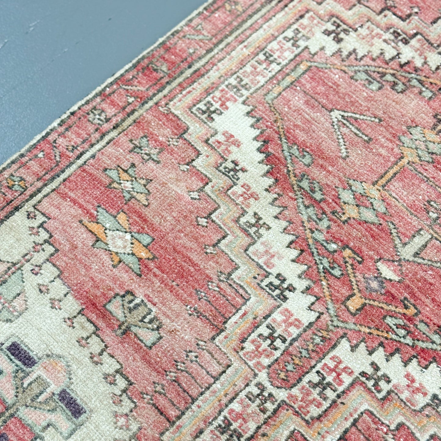 Close-up of a patterned rug with pink and beige colors.