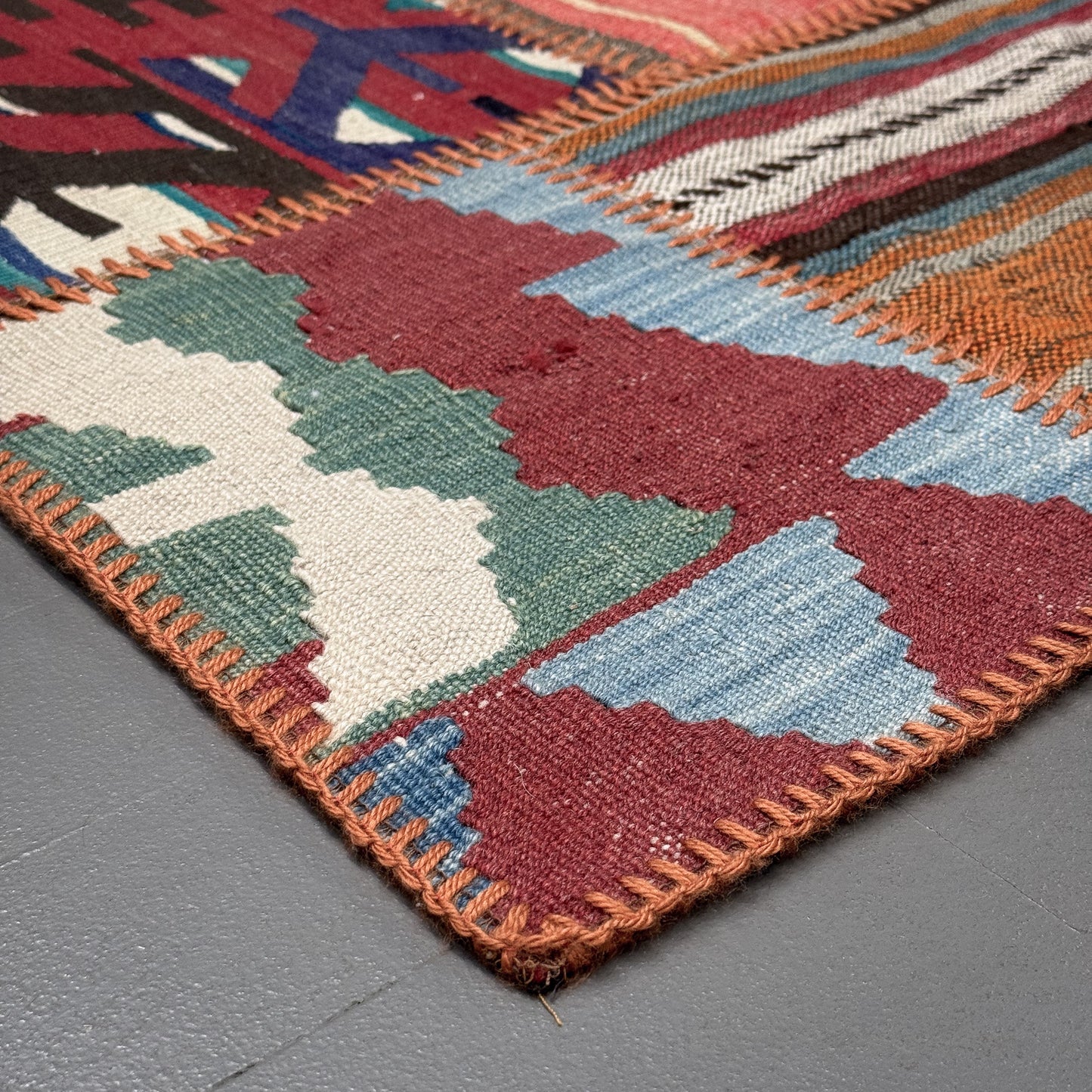 Close-up of a colorful woven rug with geometric pattern on a gray surface