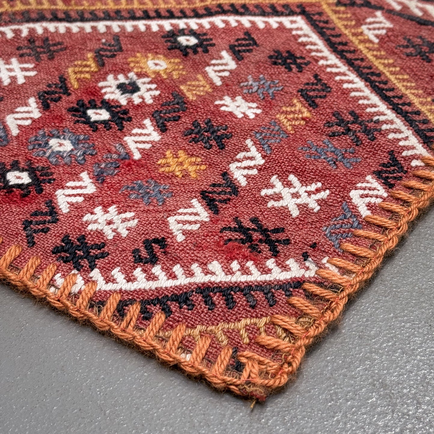 Close-up of a patterned rug corner on a gray surface
