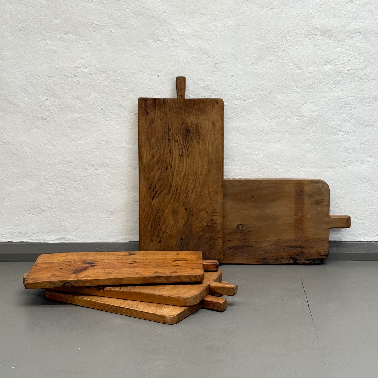 Set of wooden cutting boards on a gray floor with a white textured wall background