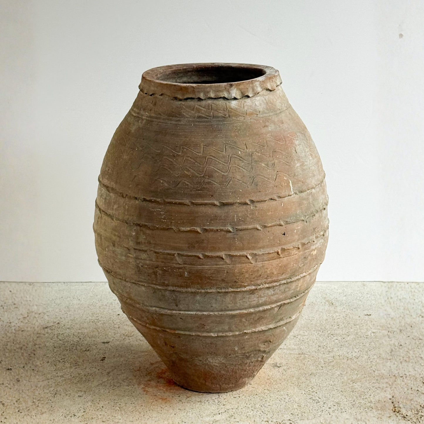 Vintage terracotta pot with textured surface on a light background