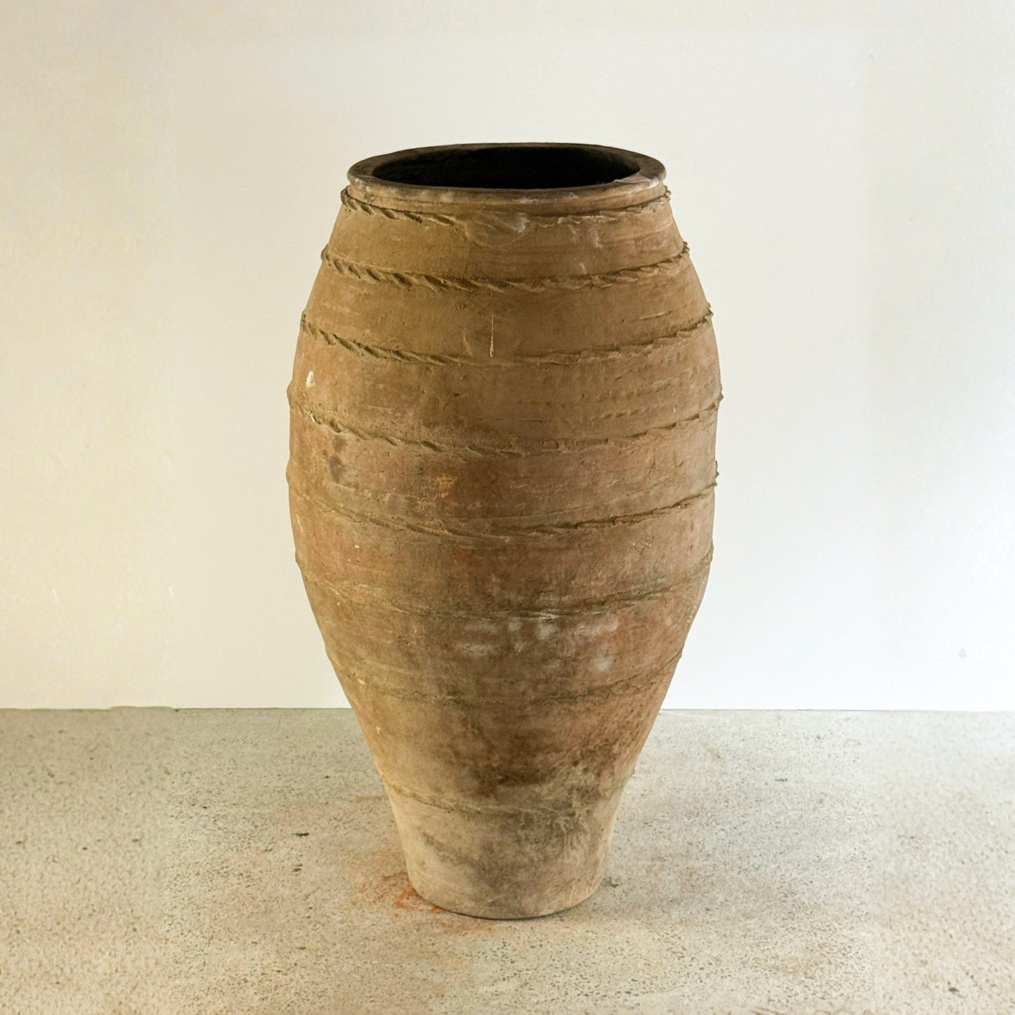 Terracotta vase with textured surface on a beige background