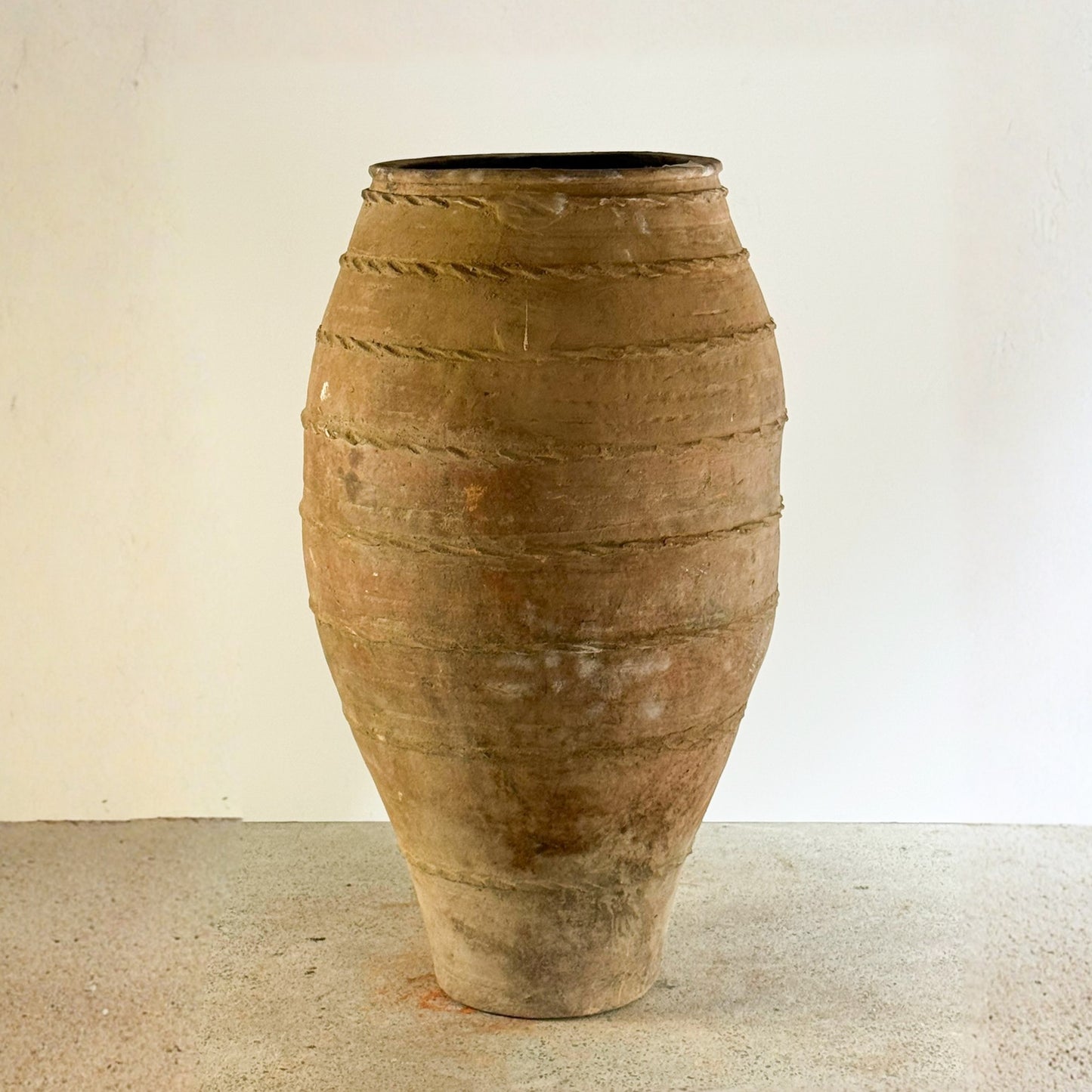 Large terracotta vase with textured surface on a plain background
