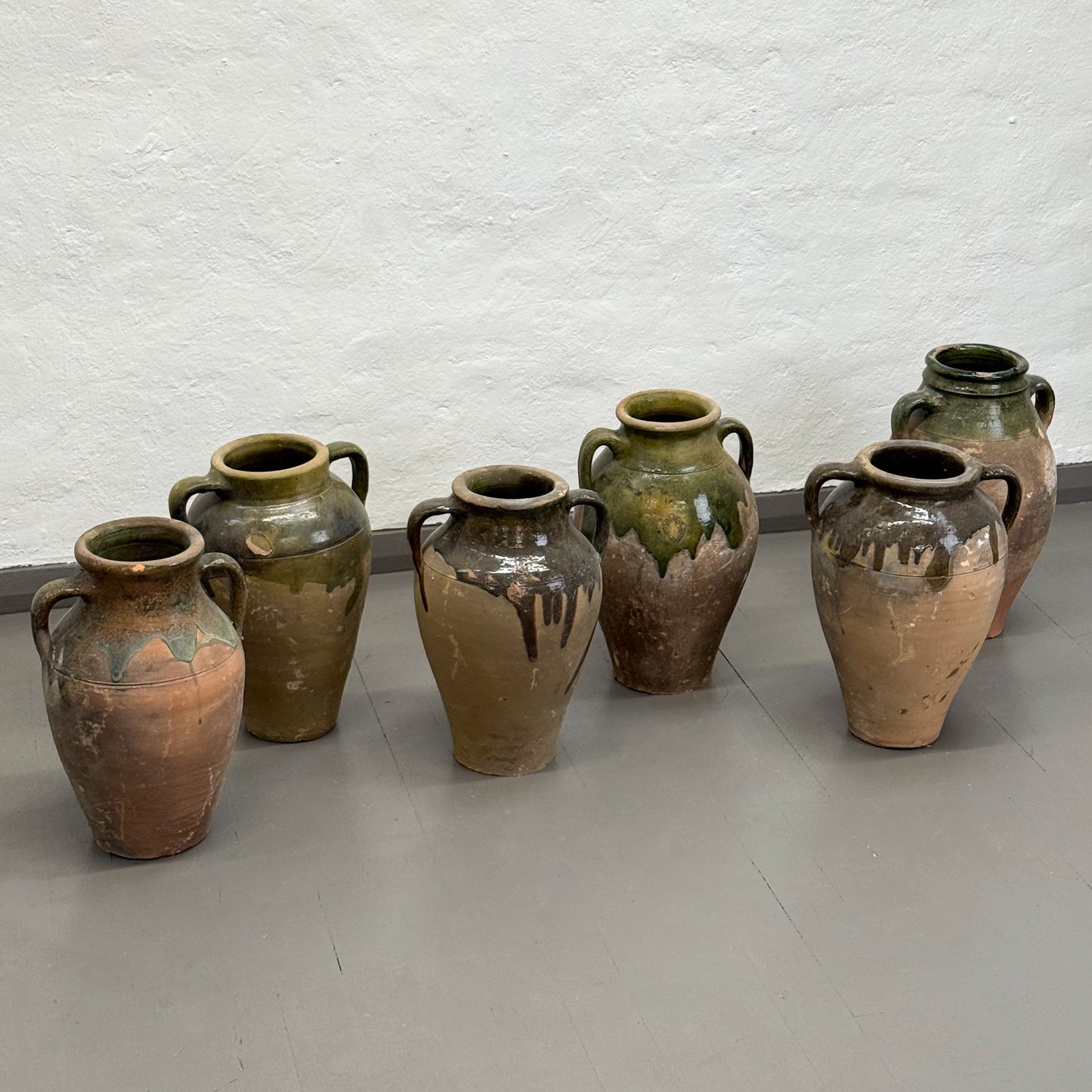 Set of six ceramic vases with varying designs on a plain floor.