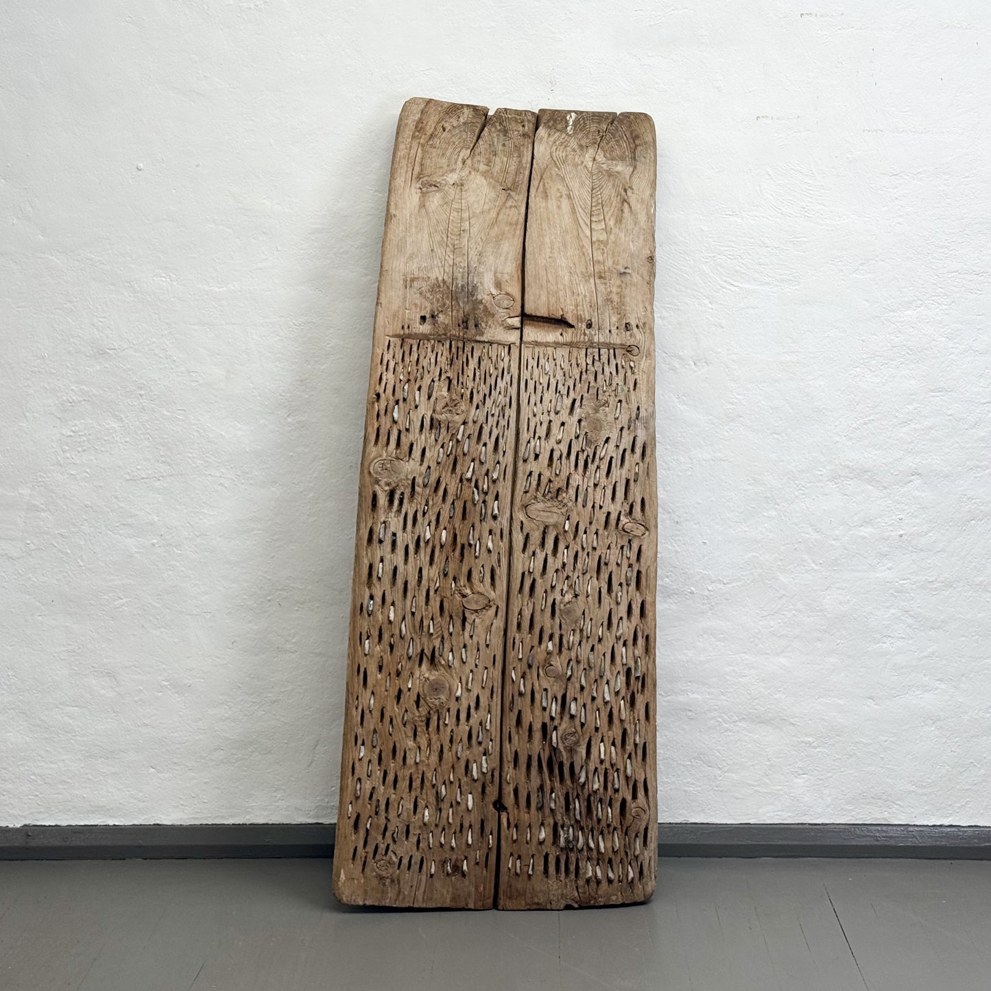 Large wooden slab with textured surface against a white wall