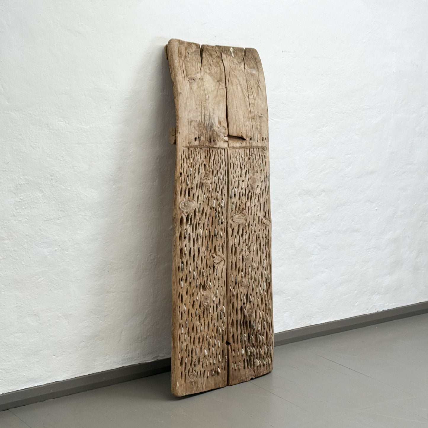 Large wooden panel leaning against a white wall