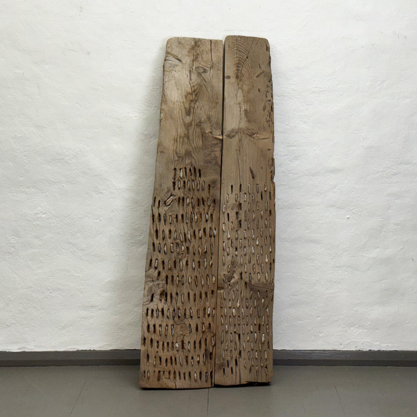 Two wooden panels with carvings against a white wall
