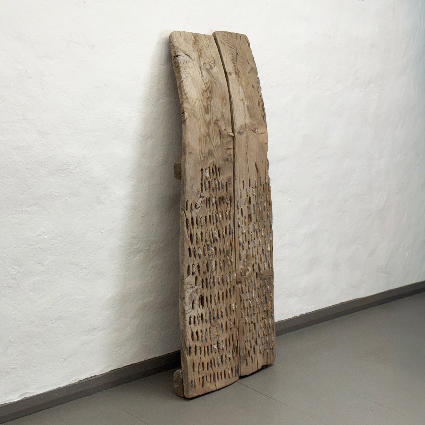 Wooden sculpture leaning against a white wall