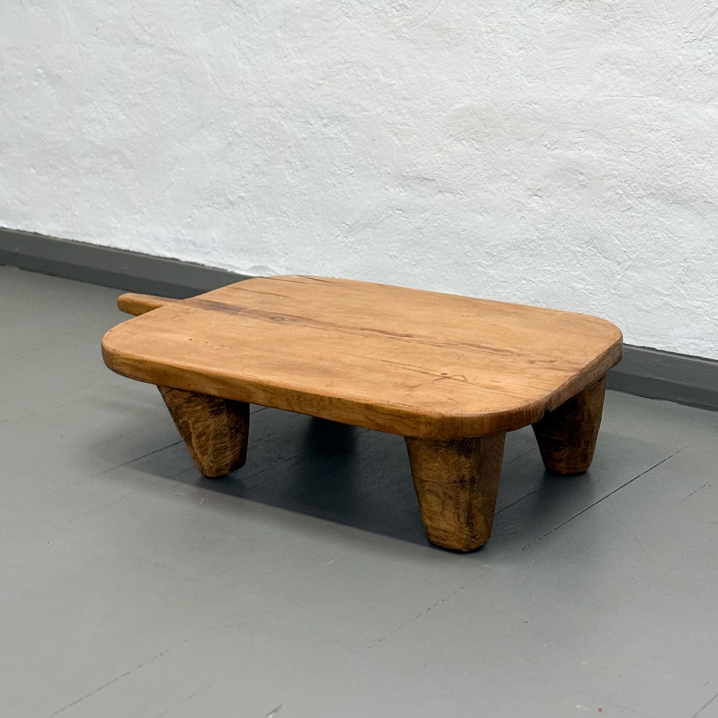 Wooden stool with a textured wall and gray floor in the background