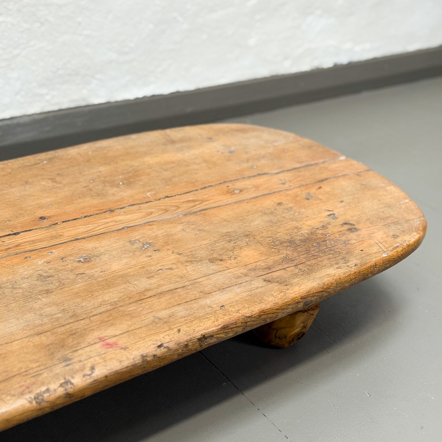 Wooden table with visible wear on a gray floor