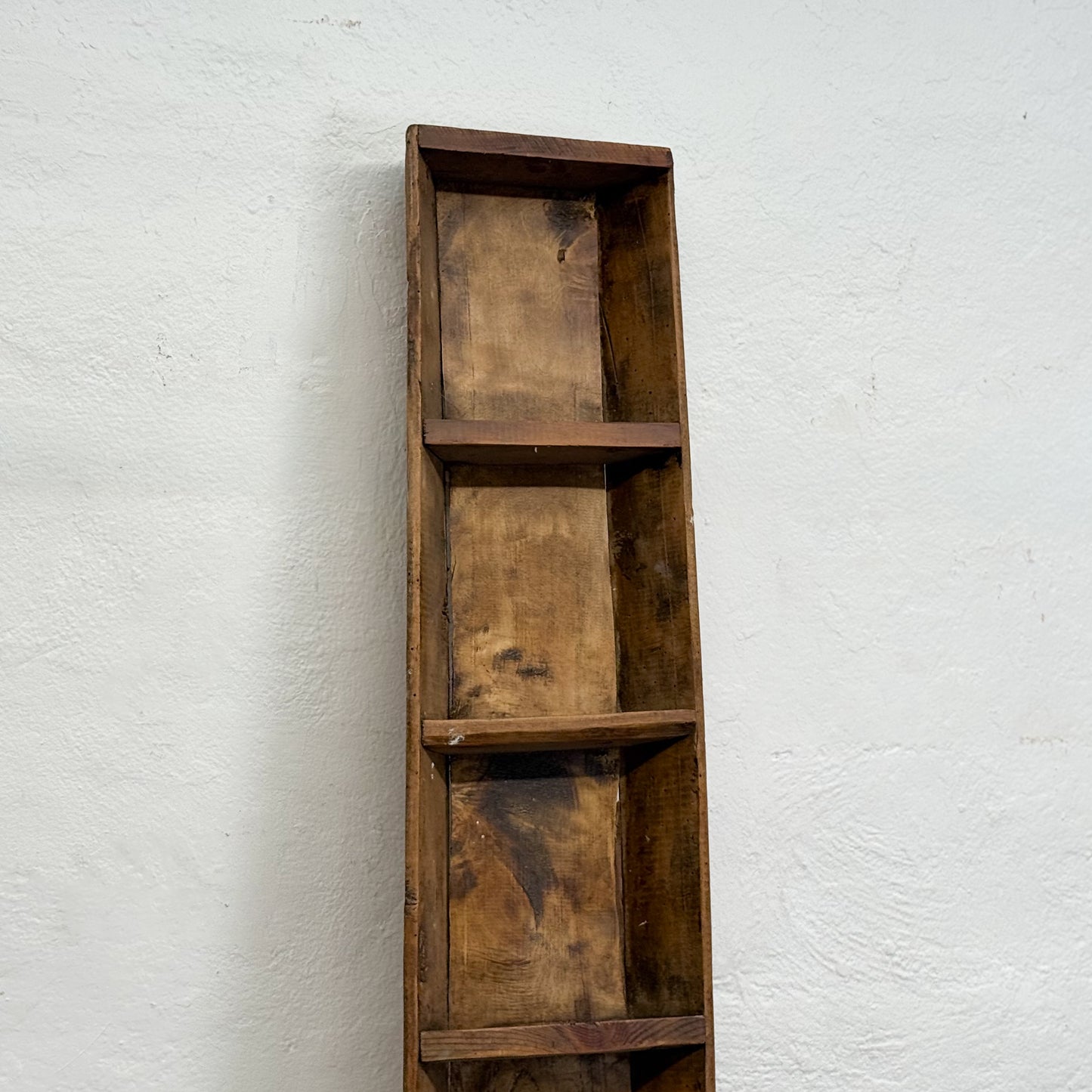Wooden shelf with three compartments against a white wall
