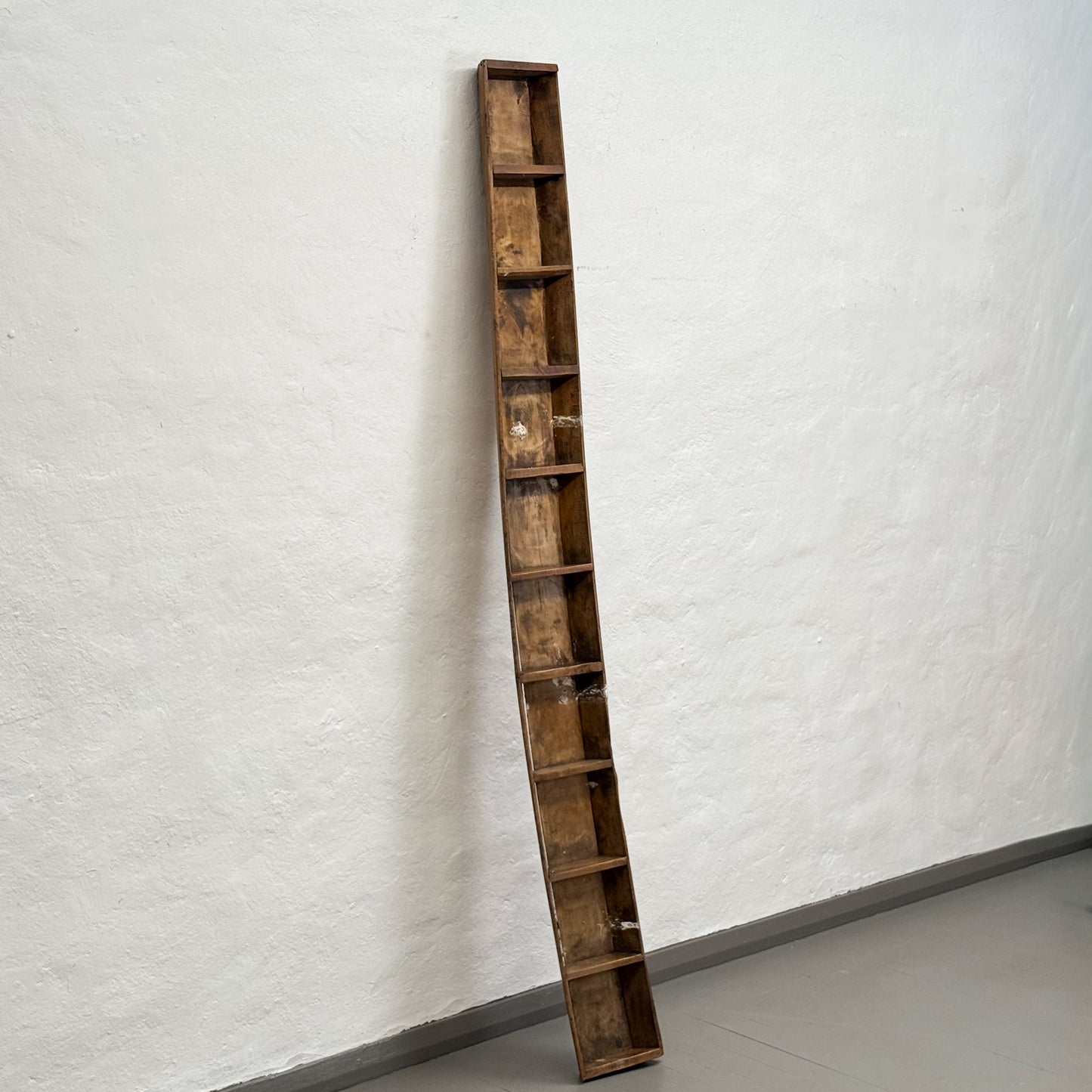 Tall wooden bookshelf against a white wall